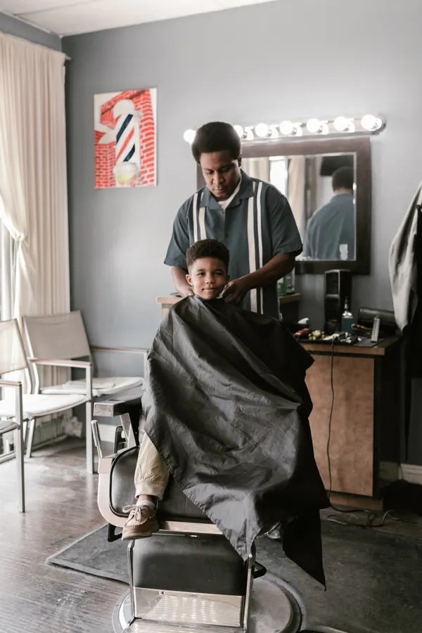 Niño recibiendo un corte en la silla de barbero