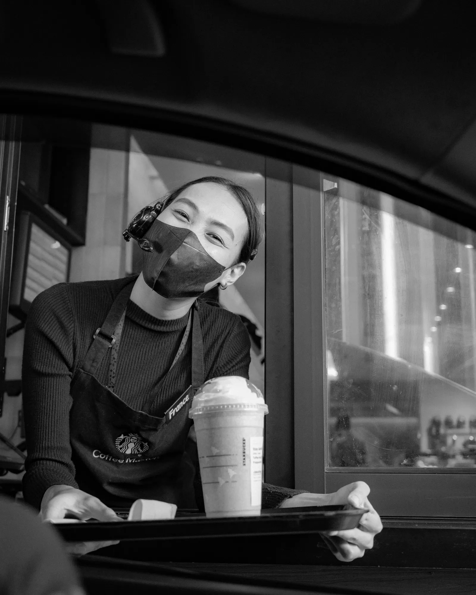 Barista entregando café por la ventana del drive-thru