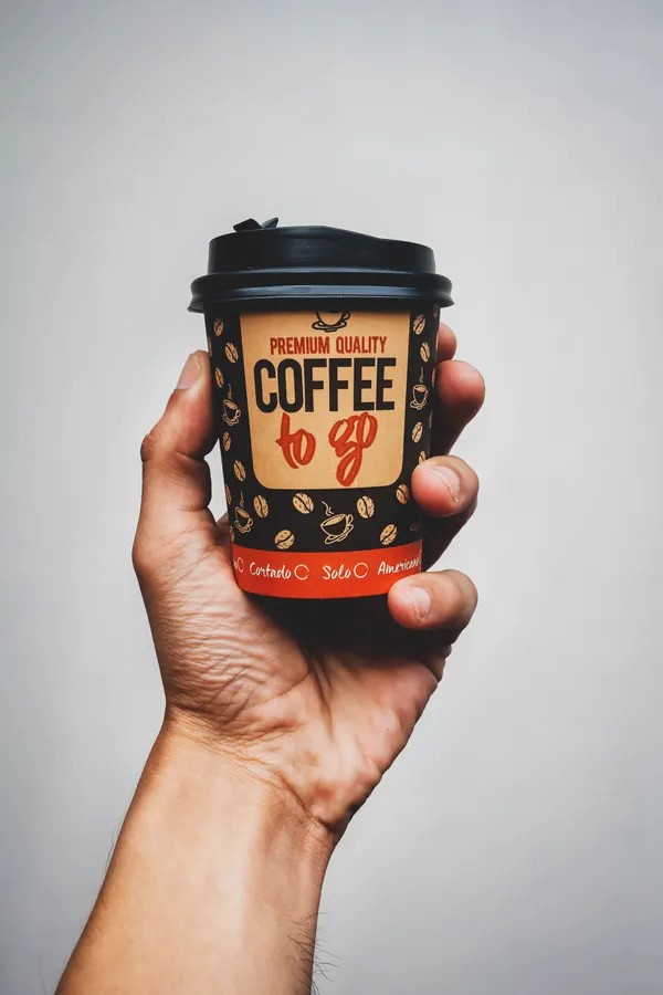 Mano sosteniendo un vaso de café para llevar