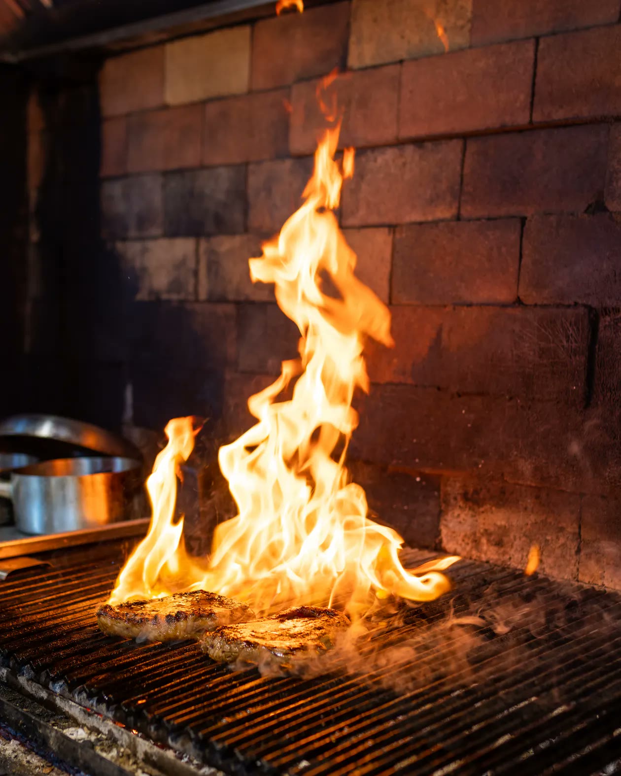 Cortes de carne sobre la parrilla entre llamas