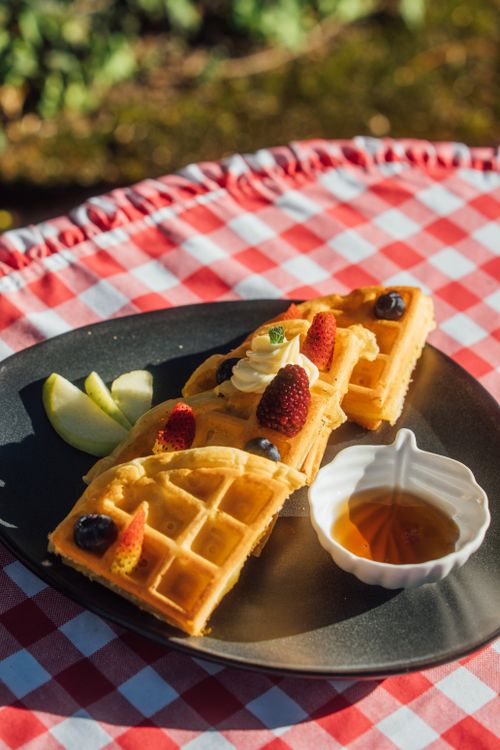 Waffles con frutas y sirope en mesa rústica
